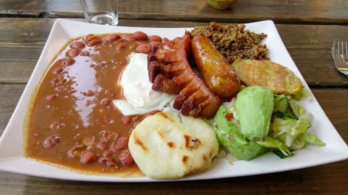 Tallrik med bönor, chorizo, arepa, plantain och avokadosallad